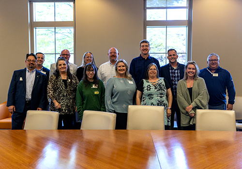 Alumni board members posing together in a meeting room