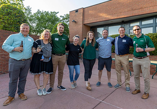 Alumni posing together outdoors during a campus gathering