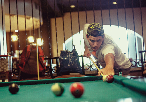 Student playing pool in a campus recreation space