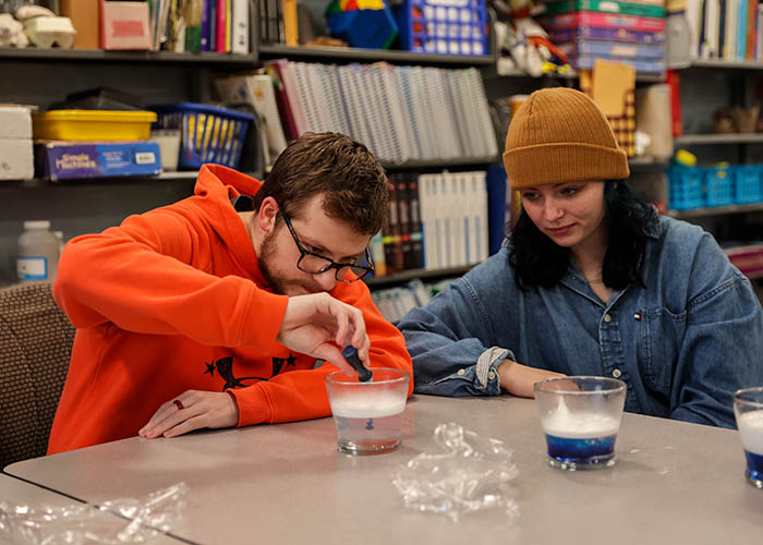 Students work together on a classroom experiment, observing liquids layered in cups.