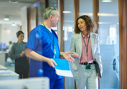 Healthcare professional and administrator walking and discussing information in a hospital hallway
