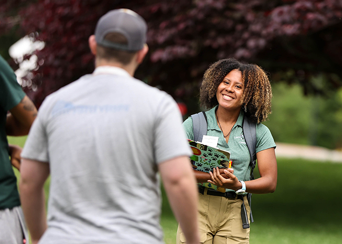 Saige Jones faces a tour group she is leading around campus. She holds a clipboard.