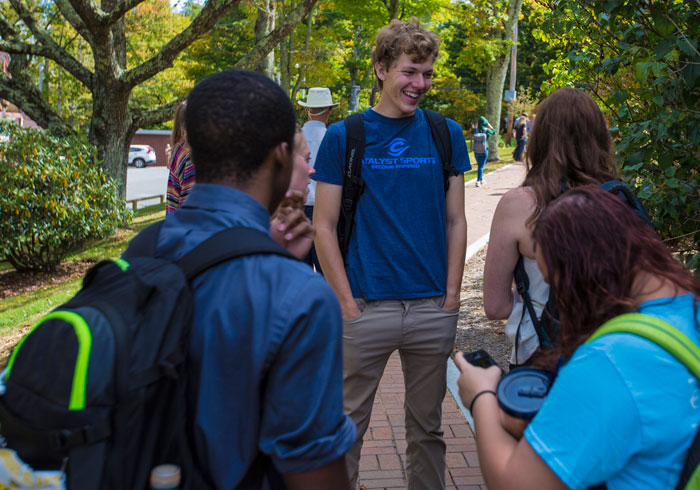 Students walking and talking together along a tree-lined campus path