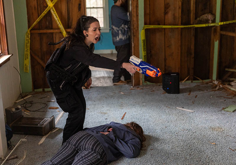 Student participates in a mock crime-scene exercise, using a training prop to signal a simulated command.