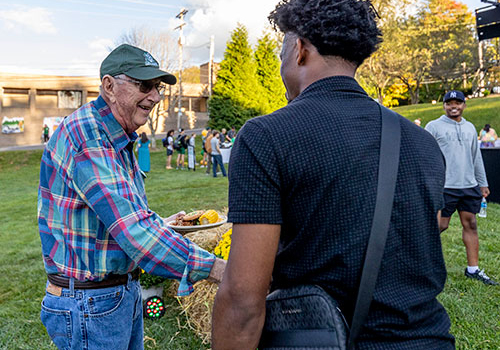 Alumni greeting each other during an outdoor campus event